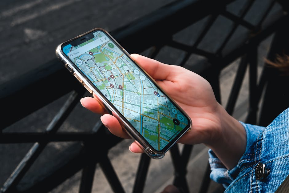An outdoor close-up of a hand holding a smartphone displaying a map application.