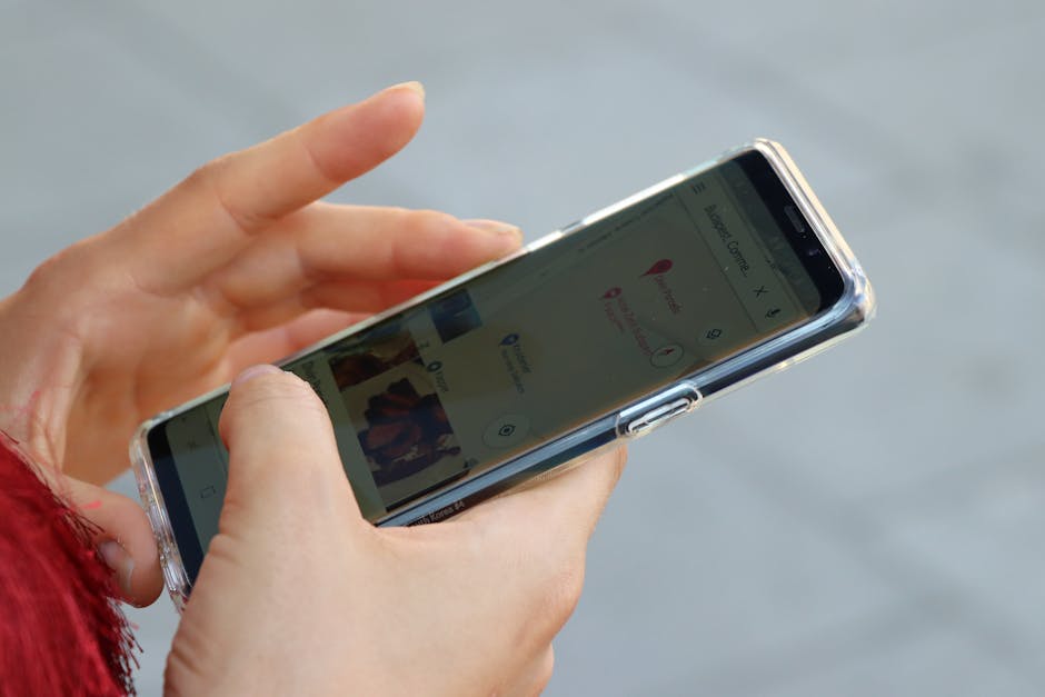 Hands holding a smartphone with a clear case, browsing a map outdoors.